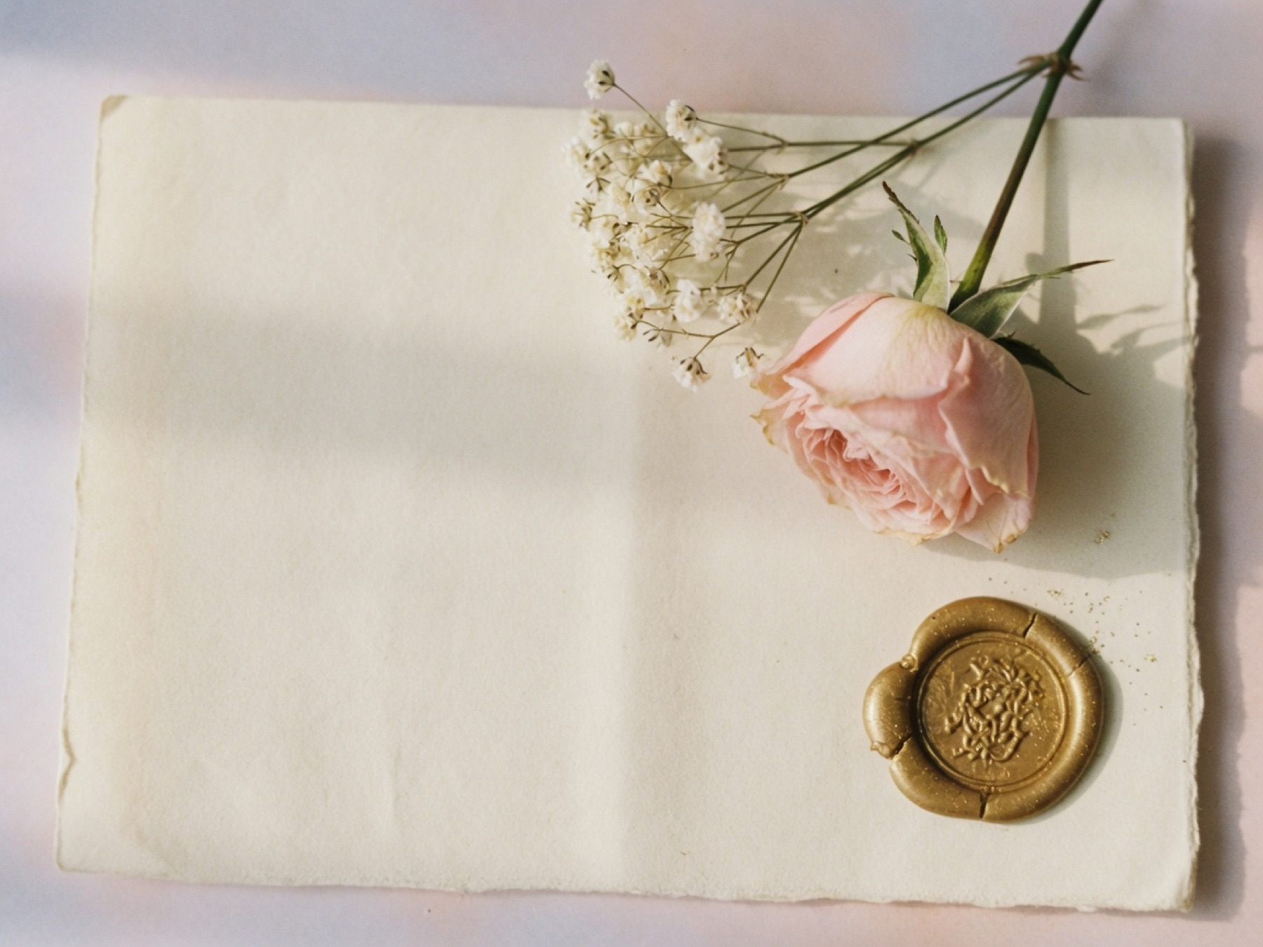 Blank cream stationery with a blush rose, baby's breath, and a gold wax seal